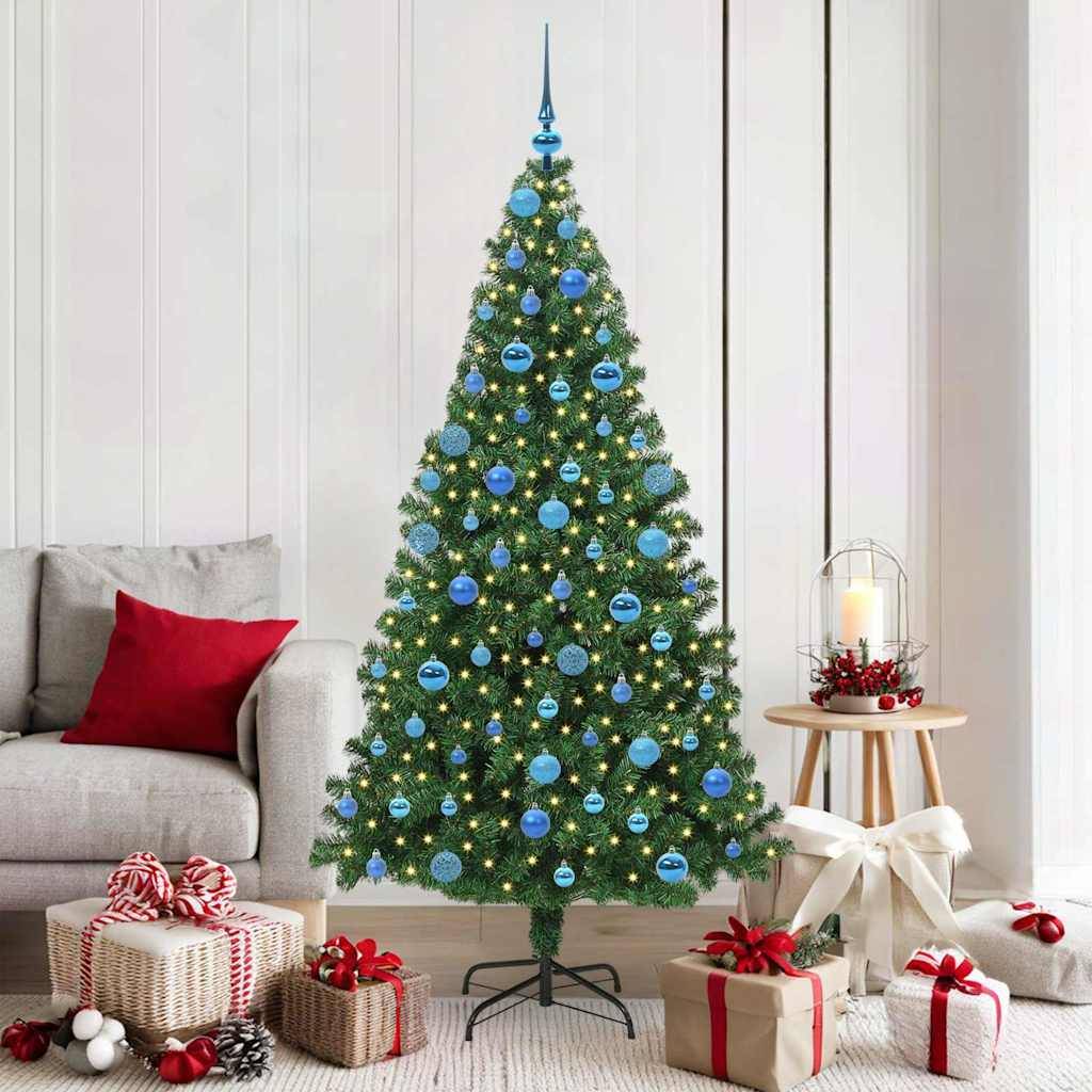 Ein geschmückter Weihnachtsbaum mit blauen Kugeln und Lichtern steht in einem Wohnzimmer neben einem Sofa mit roten Kissen und einem Geschenketisch.