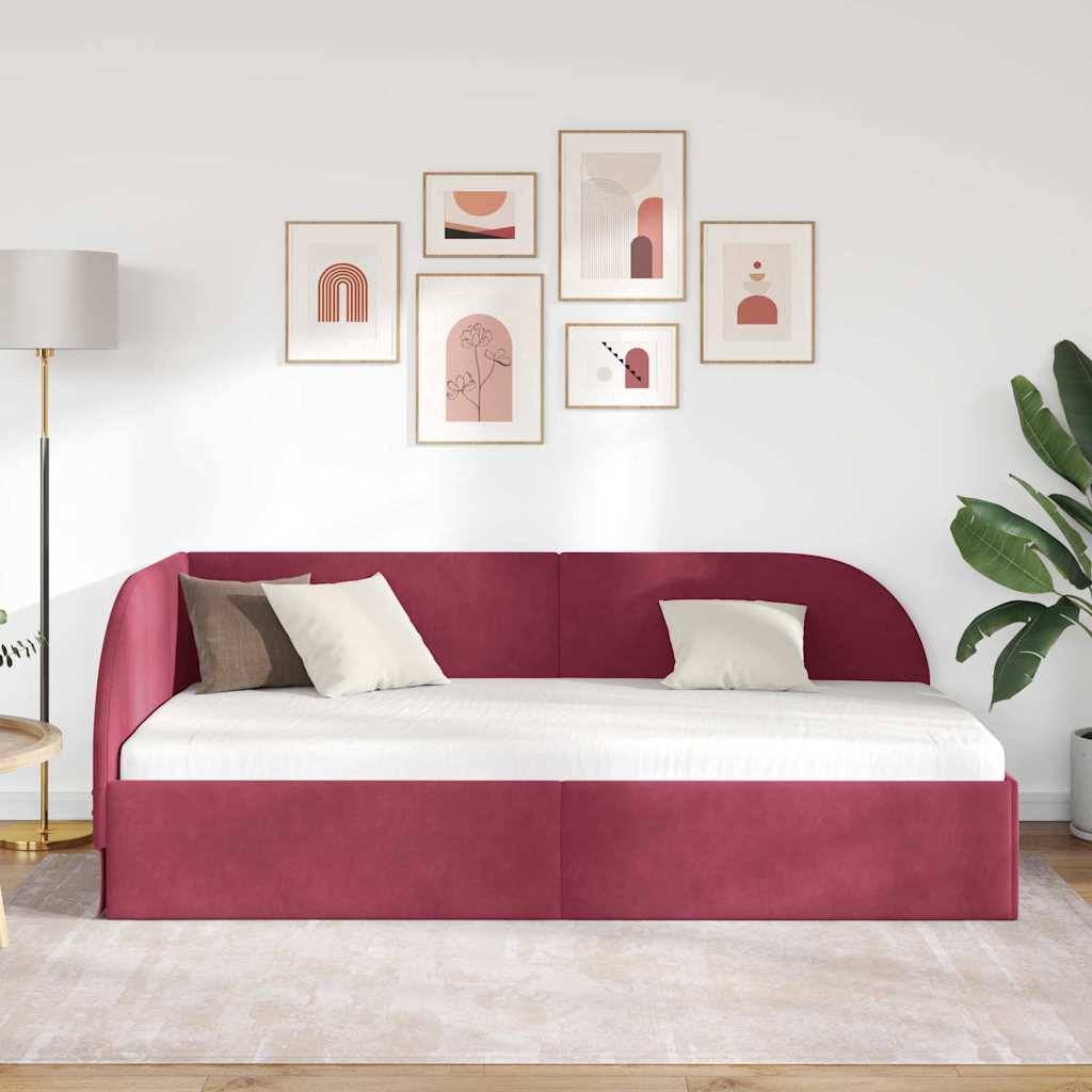 Modernes Wohnzimmer mit rotem Tagesbett, weißen Kissen, goldener Stehlampe, abstrakter Wandkunst darüber und grüner Pflanze in der Ecke.