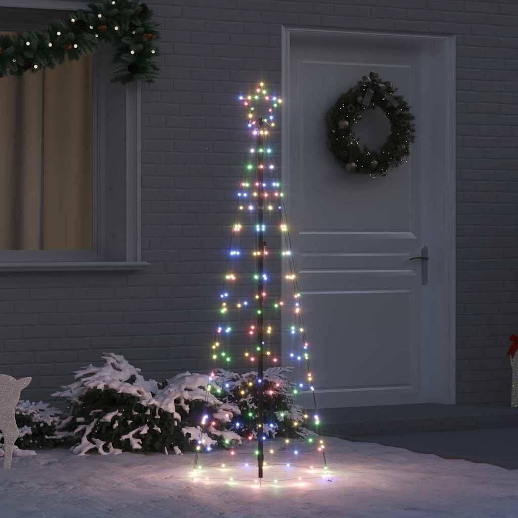 Ein minimalistischer Weihnachtsbaumrahmen mit mehrfarbigen Lichtern steht vor einem Haus, geschmückt mit einem Kranz. Schnee bedeckt die umliegende Bodenfläche.