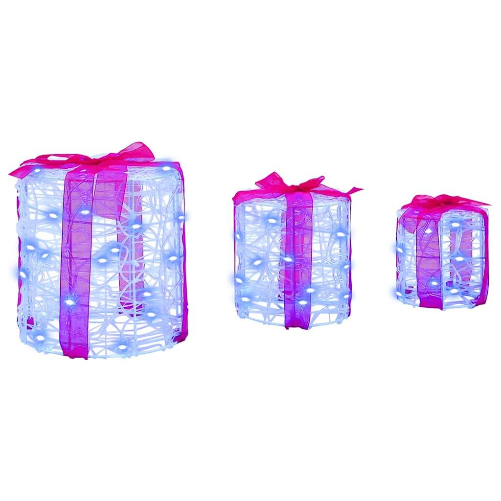 Drei transparente Geschenkboxen in aufsteigender Größe, mit rosa Bändern umwickelt und mit kleinen blauen Lichtern beleuchtet, in einer Reihe angeordnet.