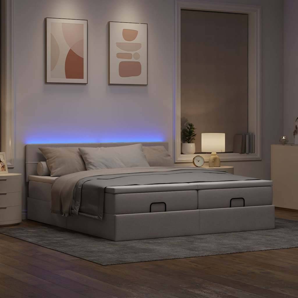 Ein modernes Schlafzimmer mit einem großen Bett, grauer Bettwäsche, Stauraum unter dem Bett, zwei abstrakten Wandkunstwerken, einer Lampe und einem Fenster. Warmes Licht schafft eine gemütliche Atmosphäre.