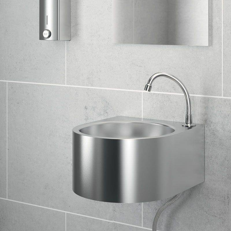 Edelstahlwaschbecken an der Wand mit gebogenem Wasserhahn in einem gefliesten Badezimmer, dargestellt unter einem Spiegel und einem Seifenspender.