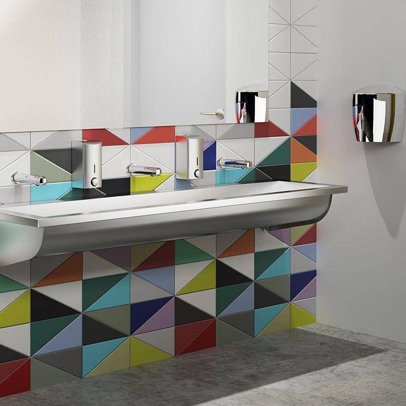 Modernes Waschbecken in öffentlicher Toilette mit drei Wasserhähnen und geometrischem mehrfarbigem gefliesten Spritzschutz und Waschtischfront