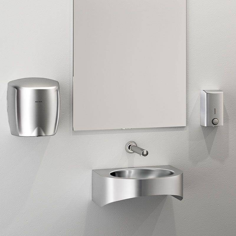 Modernes Edelstahl-Handwaschbecken für öffentliche Toiletten mit Spiegel, Seifenspender und Papiertuchspender an einer hellen Wand.