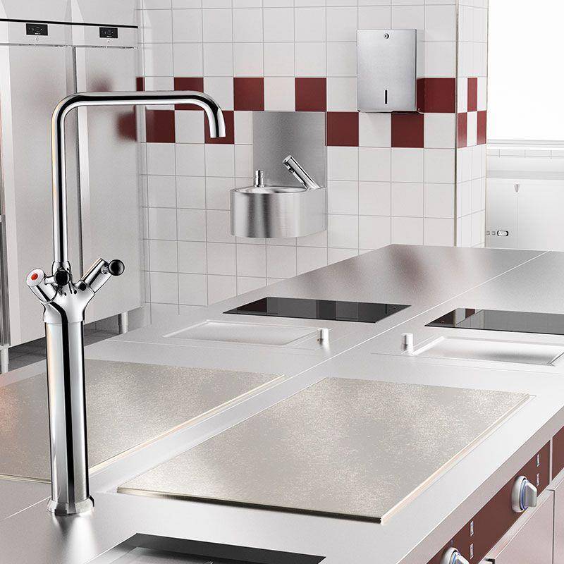 Moderne Gewerbeküche mit Edelstahlarbeitsplatten und Spülen, einem hohen verchromten Wasserhahn im Vordergrund und gekachelten Wänden mit roten Akzenten.