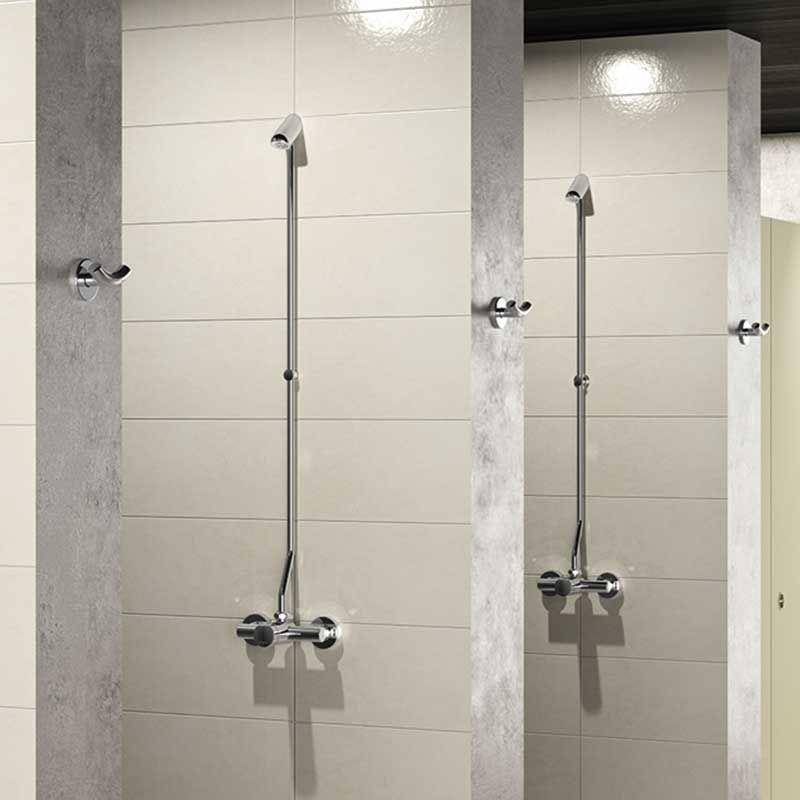Zwei minimalistische Chromduscharmatur mit Handbrausen, die auf gefliesten Badezimmerwänden in nebeneinanderliegenden Duschkabinen montiert sind.