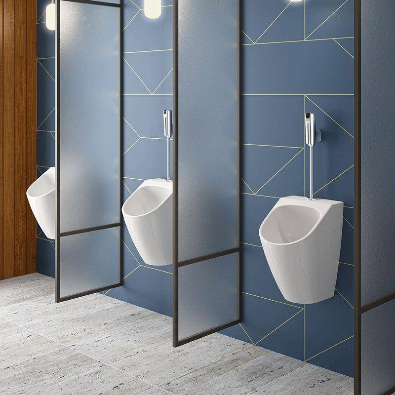 Modernes öffentliches Badezimmer mit drei wandmontiert Urinalen, die durch mattierte Datenschutztrennwände vor blauem geometrischem Fliesenbelag getrennt sind.