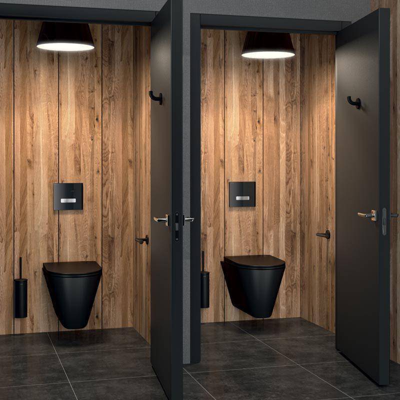 Zwei moderne Toilettenkabinen mit schwarzen Armaturen, holzgetäfelten Wänden, dunklen Fliesenböden und offenen schwarzen Türen.