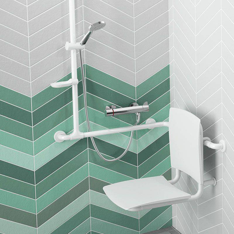 Barrierefreie Dusche mit weißer Haltestange, Sitz und tragbarem Duschkopf in einem gefliesten Eckbadezimmer mit grünen und grauen Fischgrät-Fliesen.