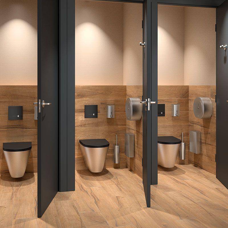 Drei moderne Toilettenkabinen mit offenen Türen, jede mit einer wandmontierten Toilette, Spülpaneelen und neutralen Holz- und Beigeoberflächen.