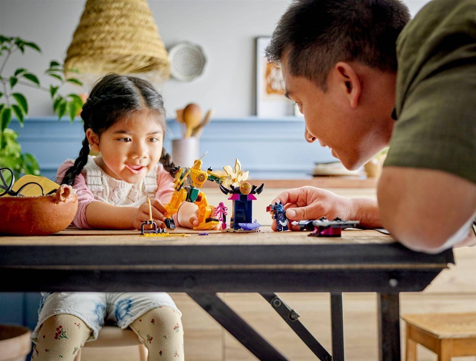 Ein Mann und ein junges Mädchen spielen mit Spielfiguren an einem Tisch, beugen sich gegenseitig zu in einer hellen Wohnungseinrichtung.