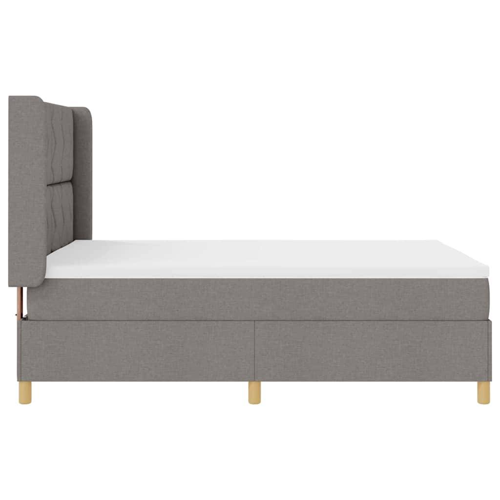Ein graues gepolstertes Bett mit einer gesteppten Kopfstütze und Holzbeinen, von der Seite betrachtet.