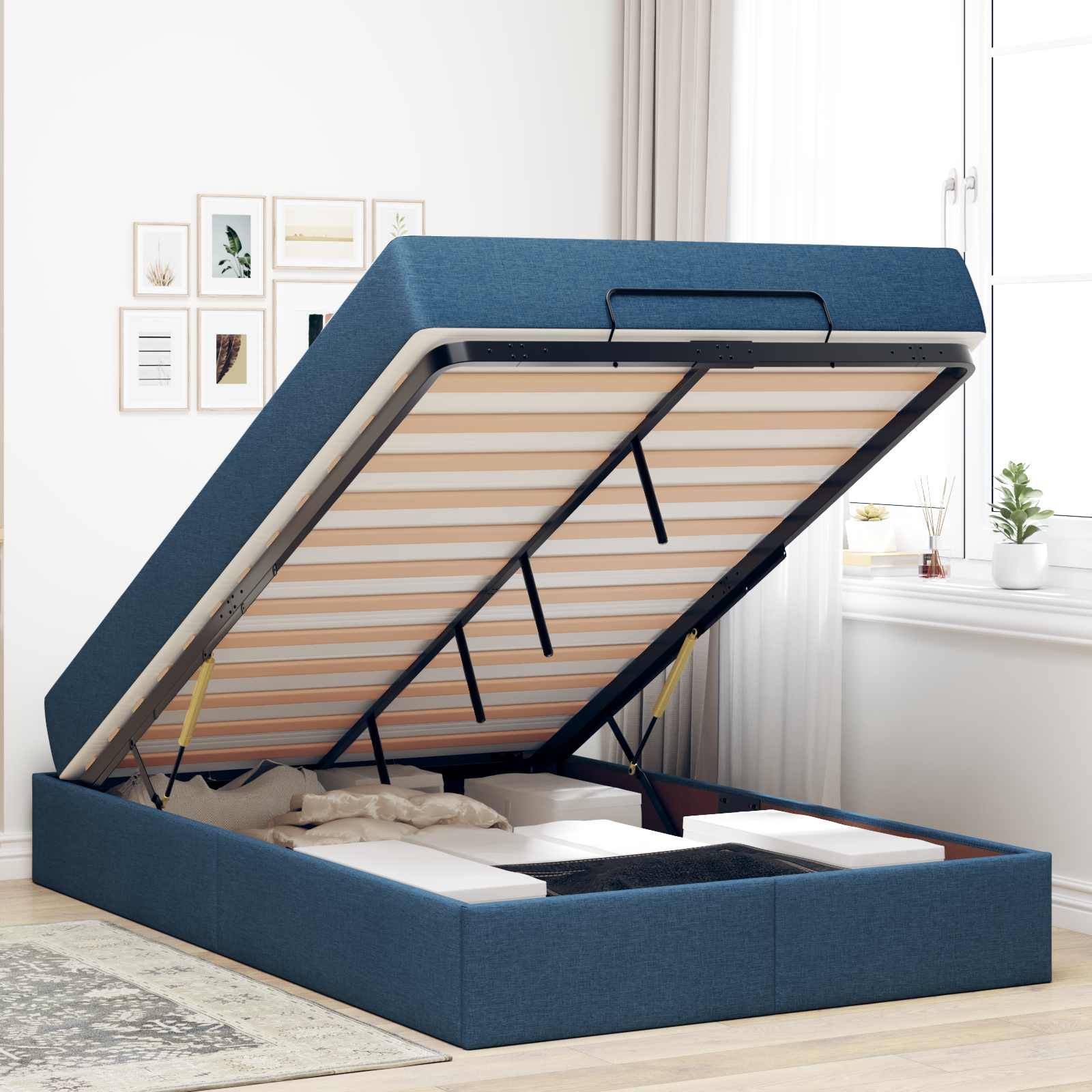 Ein blau gepolstertes Speicherbett mit offenem Deckel, der Platz darunter zum Lagern von Gegenständen freilegt. Es steht in einem hellen Raum mit einem Fenster.