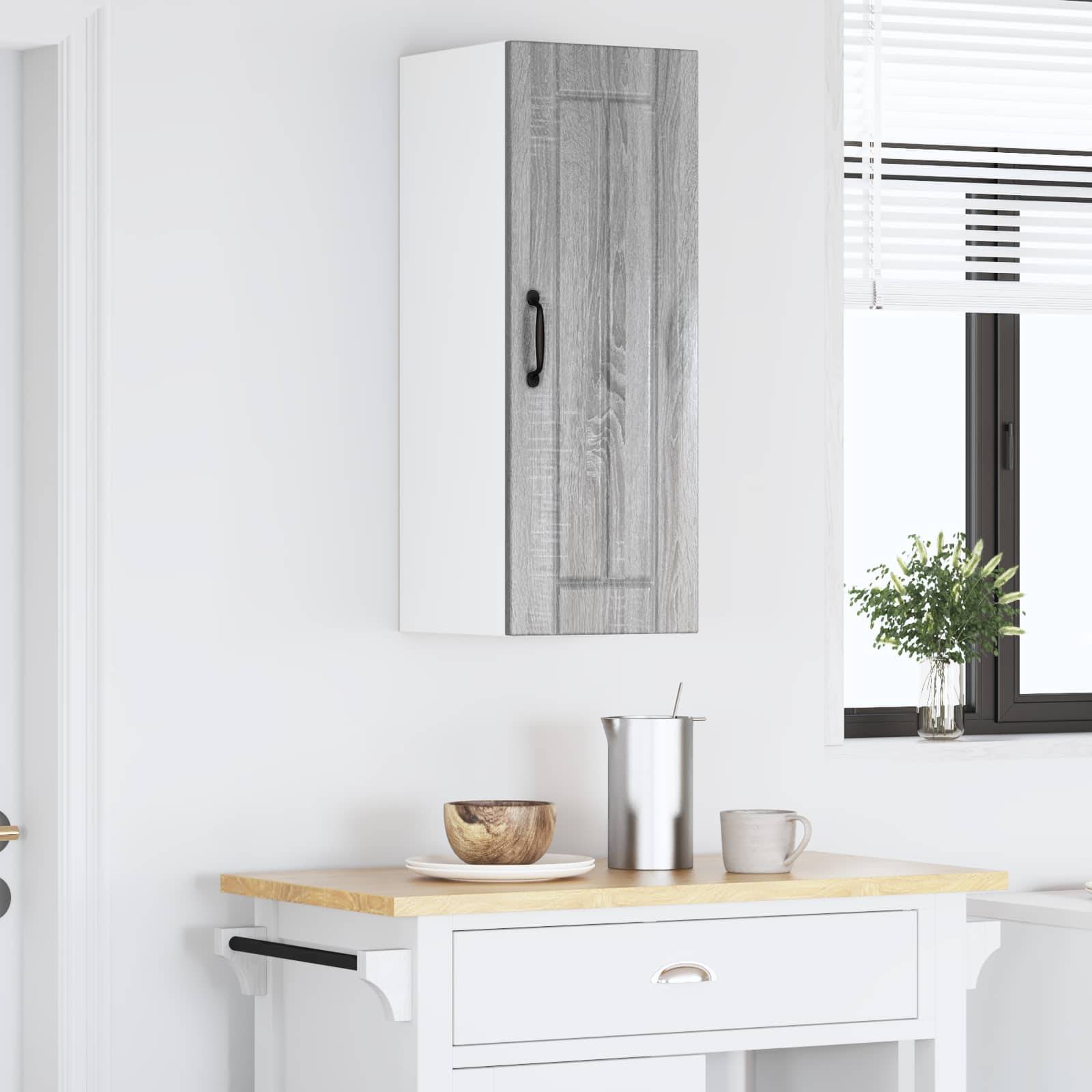 Eine moderne Kücheneinrichtung mit einem weißen Schrank, der eine Holztür und einen schwarzen Griff hat, über einer Arbeitsplatte mit einer Schüssel und einer Tasse.
