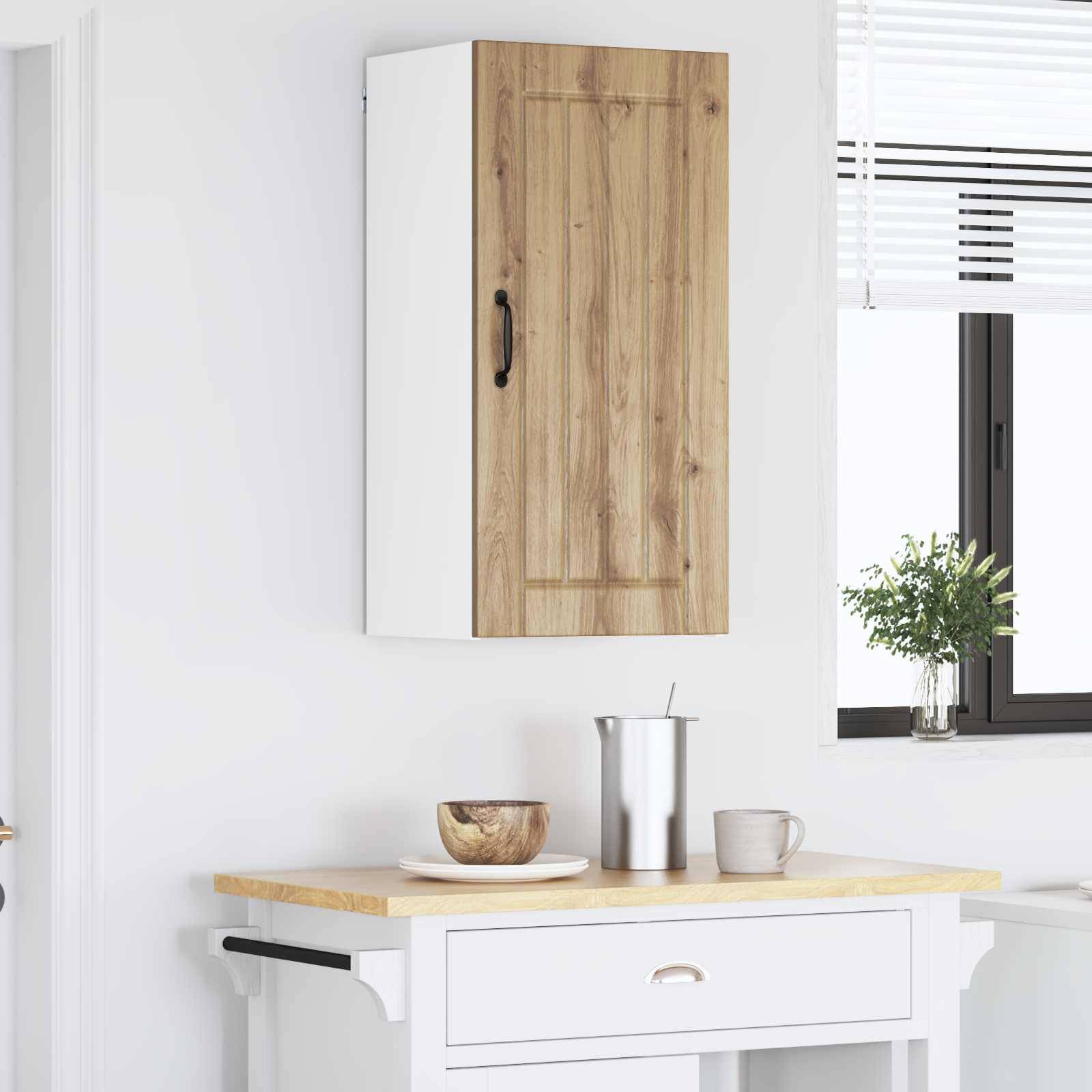 Eine moderne Küchenecke mit weißen Wänden zeigt einen kleinen Schrank über einer Arbeitsplatte. Eine Topfpflanze steht auf dem Fenstersims daneben.