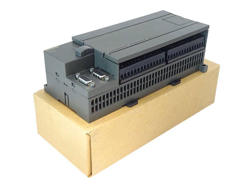 Graues industrielles Elektronikmodul bzw. Steuergerät auf einem Karton vor weißem Hintergrund.