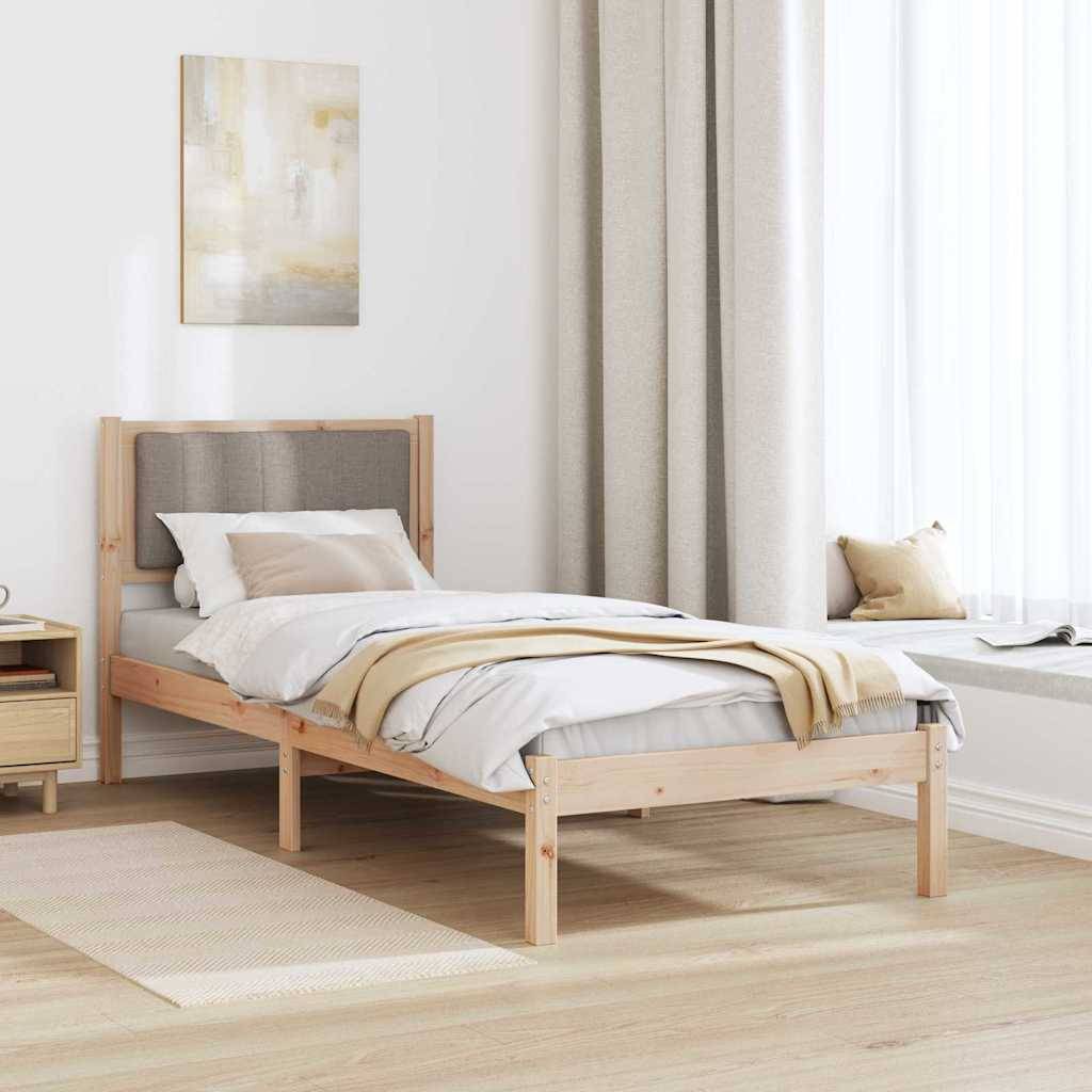 Schlafzimmer mit einem hellen Holzbett, grauem Stoffkopfteil, beigefarbener Bettwäsche und einem Nachttisch. Ein Fenster mit Vorhängen lässt natürliches Licht herein.