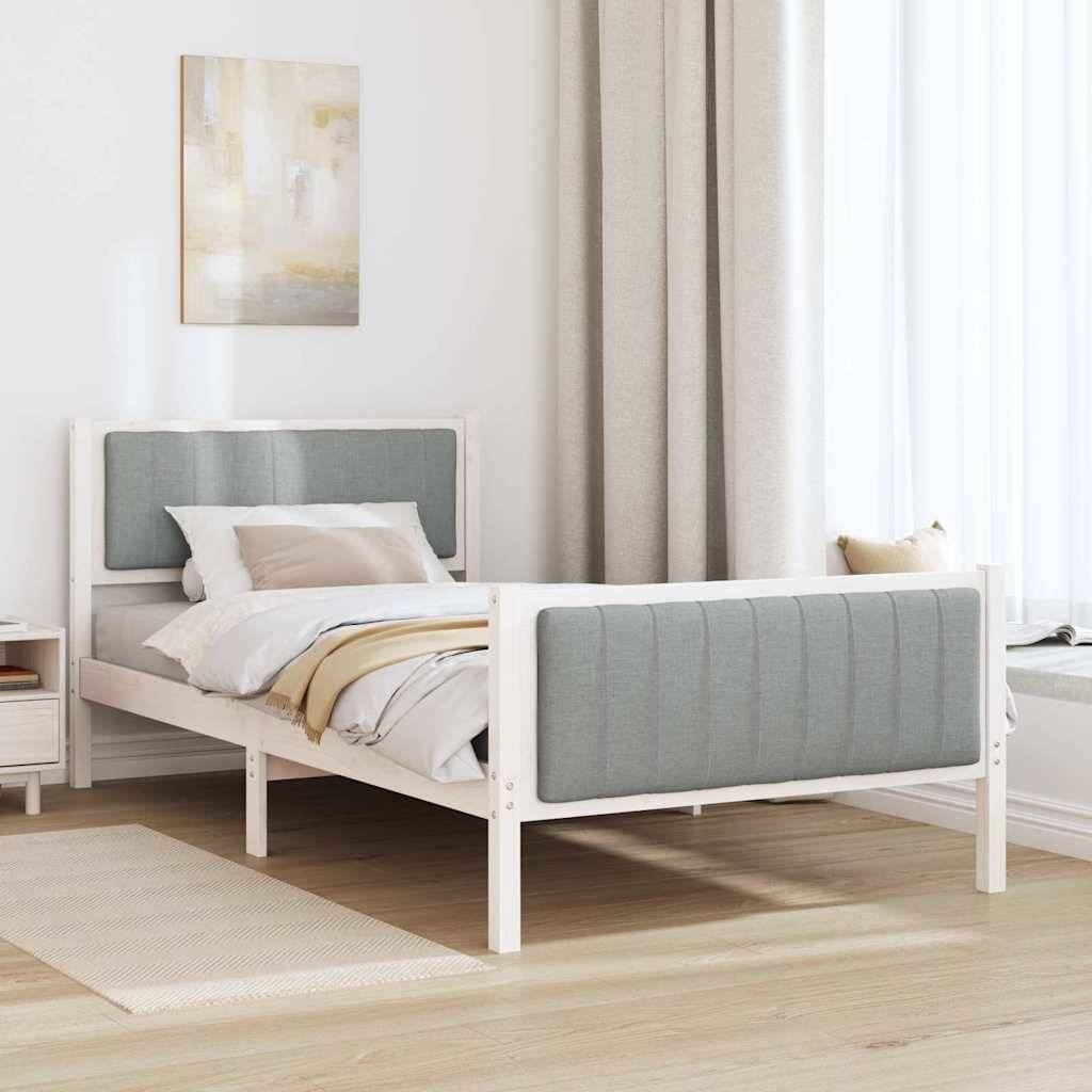 Ein ordentlich gemachtes Bett mit grau gepolstertem Kopf- und Fußteil steht in einem minimalistischen Schlafzimmer. Ein kleiner Nachttisch mit einer Lampe befindet sich daneben.