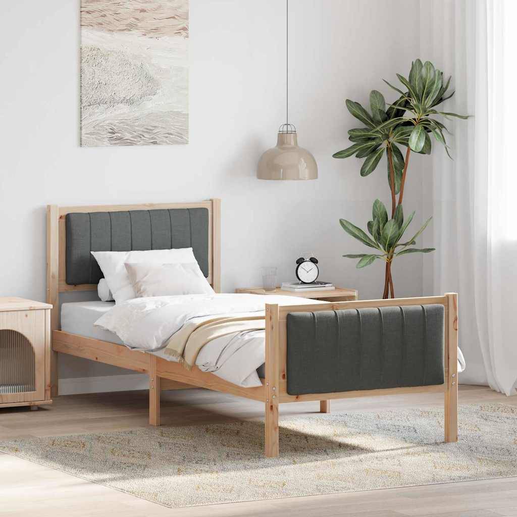 Ein Holzbett mit grauem Stoff-Kopfteil und Fußteil steht in einem hellen Zimmer, begleitet von einem Nachttisch, einer Topfpflanze und Wandkunst.