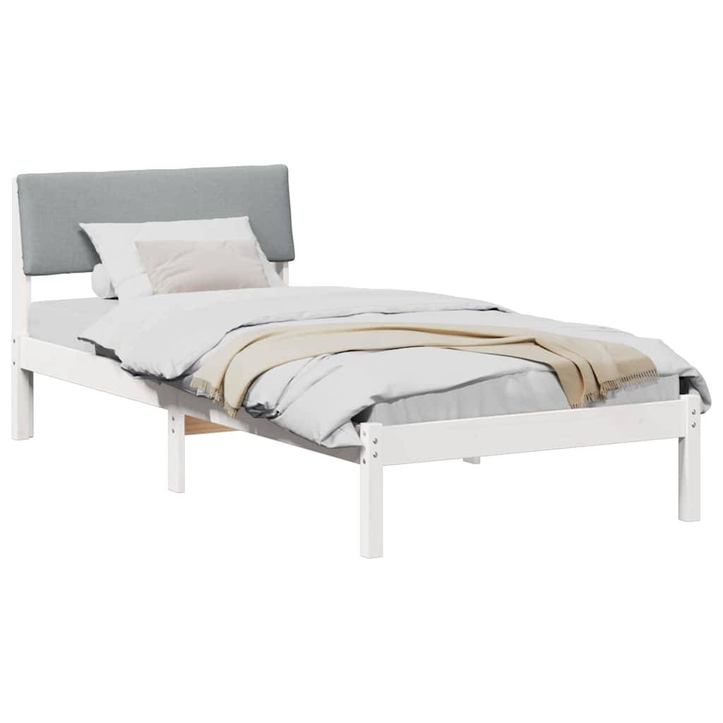 Ein Einzelbett mit weißem Rahmen, hellgrauem Kopfteil und weißer Bettwäsche mit einer beigen Decke und zwei Kissen.