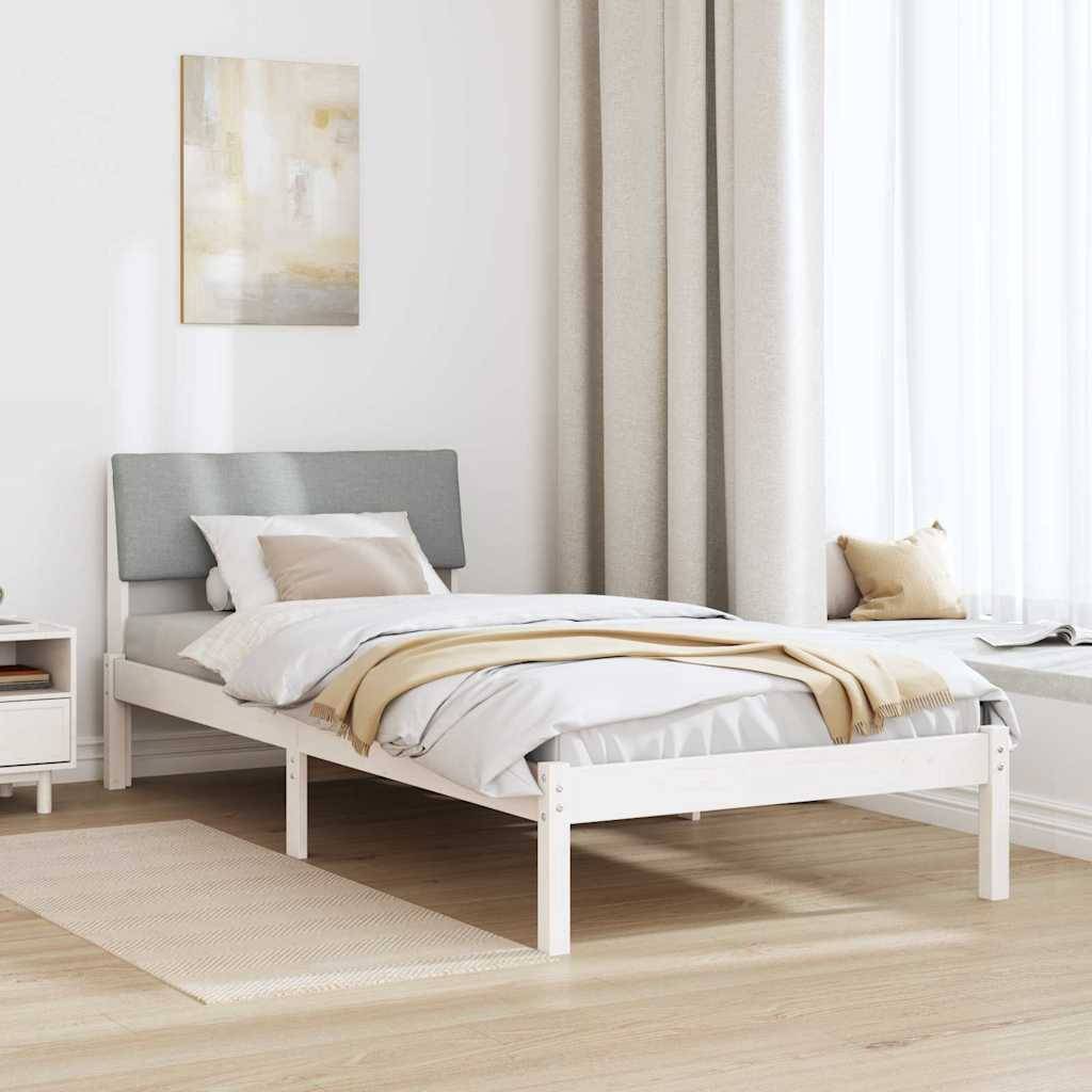Ein aufgeräumtes Schlafzimmer mit einem weißen Bett, das graue Kissen und beige Bettwäsche trägt, neben einem weißen Nachttisch mit einer Lampe und abstrakter Kunst an der Wand.