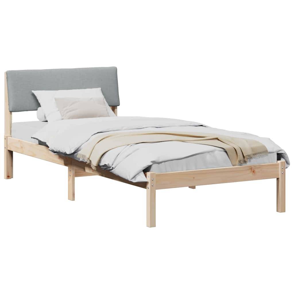 Ein Holz-Doppelbett mit einem grauen Kopfteil, weißen Laken und einer hellbeigen Decke. Ein einzelnes weißes Kissen liegt in der Nähe des Kopfteils.