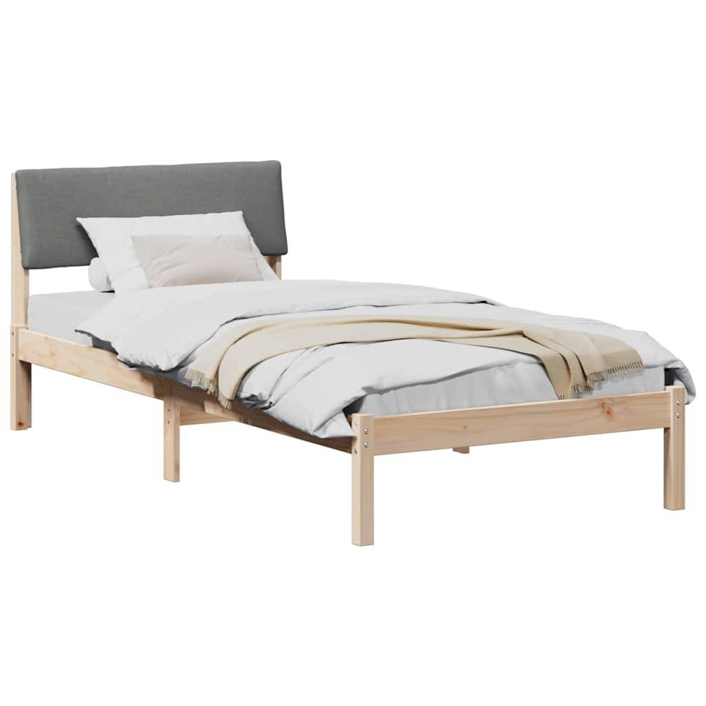 Ein Holzbettgestell mit einem grauen gepolsterten Kopfteil, ordentlich bezogen mit weißen und beigen Bettwäschestücken, vor einem weißen Hintergrund platziert.