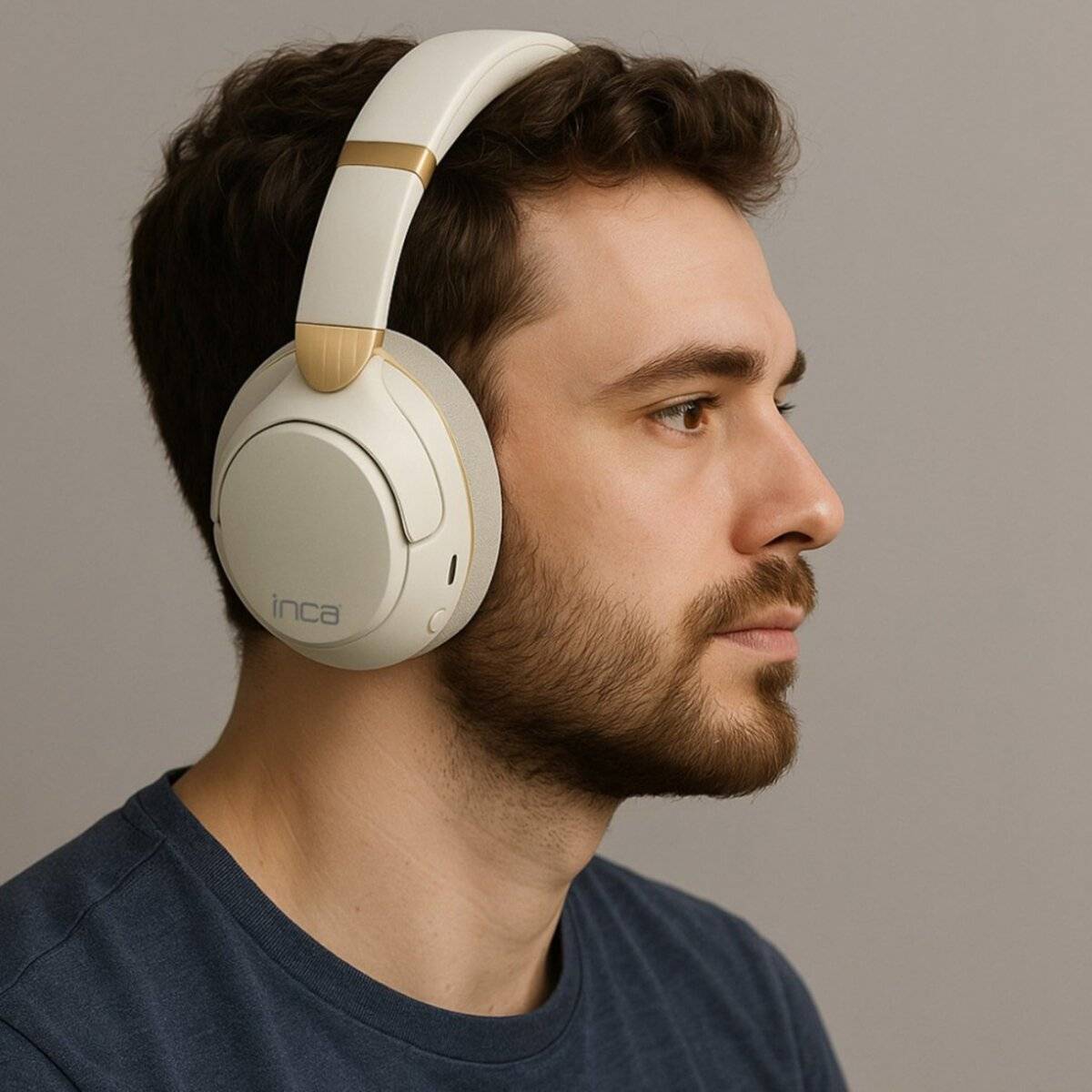Eine Person mit Over-Ear-Kopfhörern, seitlich blickend. Die Kopfhörer sind weiß mit goldenen Akzenten, und der Gesichtsausdruck der Person ist neutral.