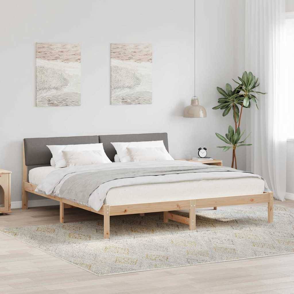 Ein minimalistisches Schlafzimmer mit einem Holzbettgestell, hellgrauer Bettwäsche und zwei abstrakten Gemälden darüber. Eine Topfpflanze und eine Lampe befinden sich rechts.