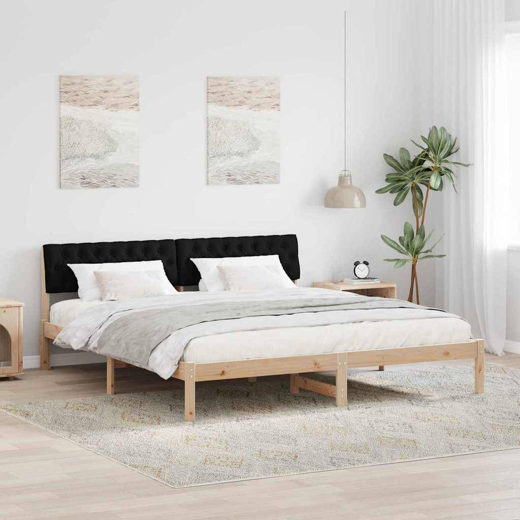 Ein minimalistisches Schlafzimmer mit einem Holzbettgestell, weißer Bettwäsche und einem schwarzen Kopfteil. Zwei abstrakte Kunstwerke hängen über dem Bett. Eine Topfpflanze und ein Nachttisch befinden sich in der Nähe.