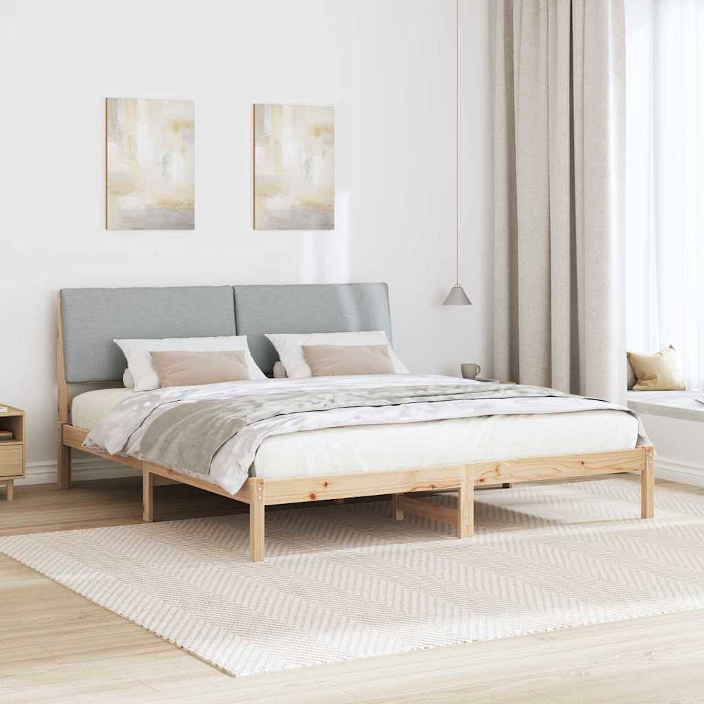 Minimalistisches Schlafzimmer mit einem Holzbettgestell, grauem Kopfteil und beigefarbener Bettwäsche. Zwei abstrakte Gemälde hängen an der weißen Wand.