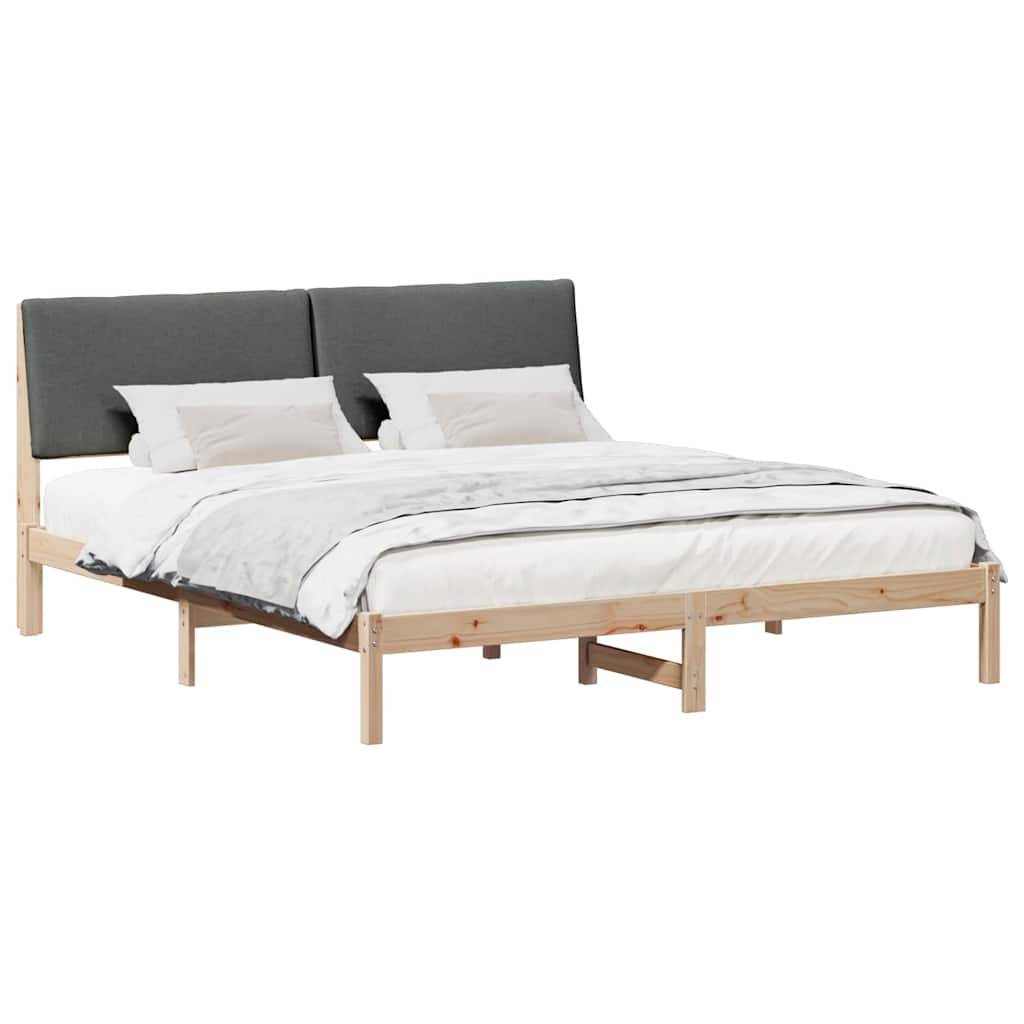 Ein Holzbettgestell mit einem grauen gepolsterten Kopfteil, weißer Bettwäsche und zwei Kissen, von einem Winkel aus auf weißem Hintergrund betrachtet.