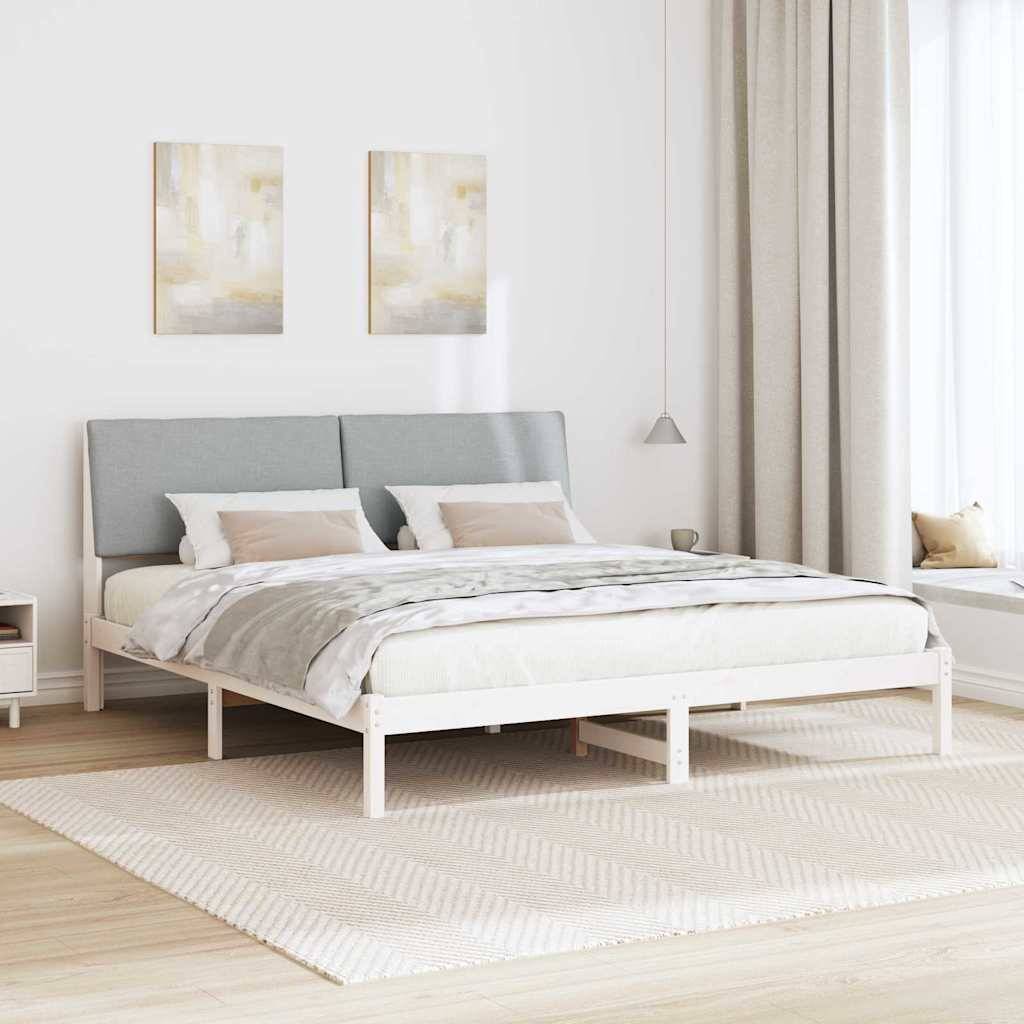 Ein modernes Schlafzimmer mit einem großen Bett, das mit weißer und beiger Bettwäsche bezogen ist, zwei abstrakten Gemälden darüber und natürlichem Licht, das durch ein Fenster mit Vorhängen hereinfällt.