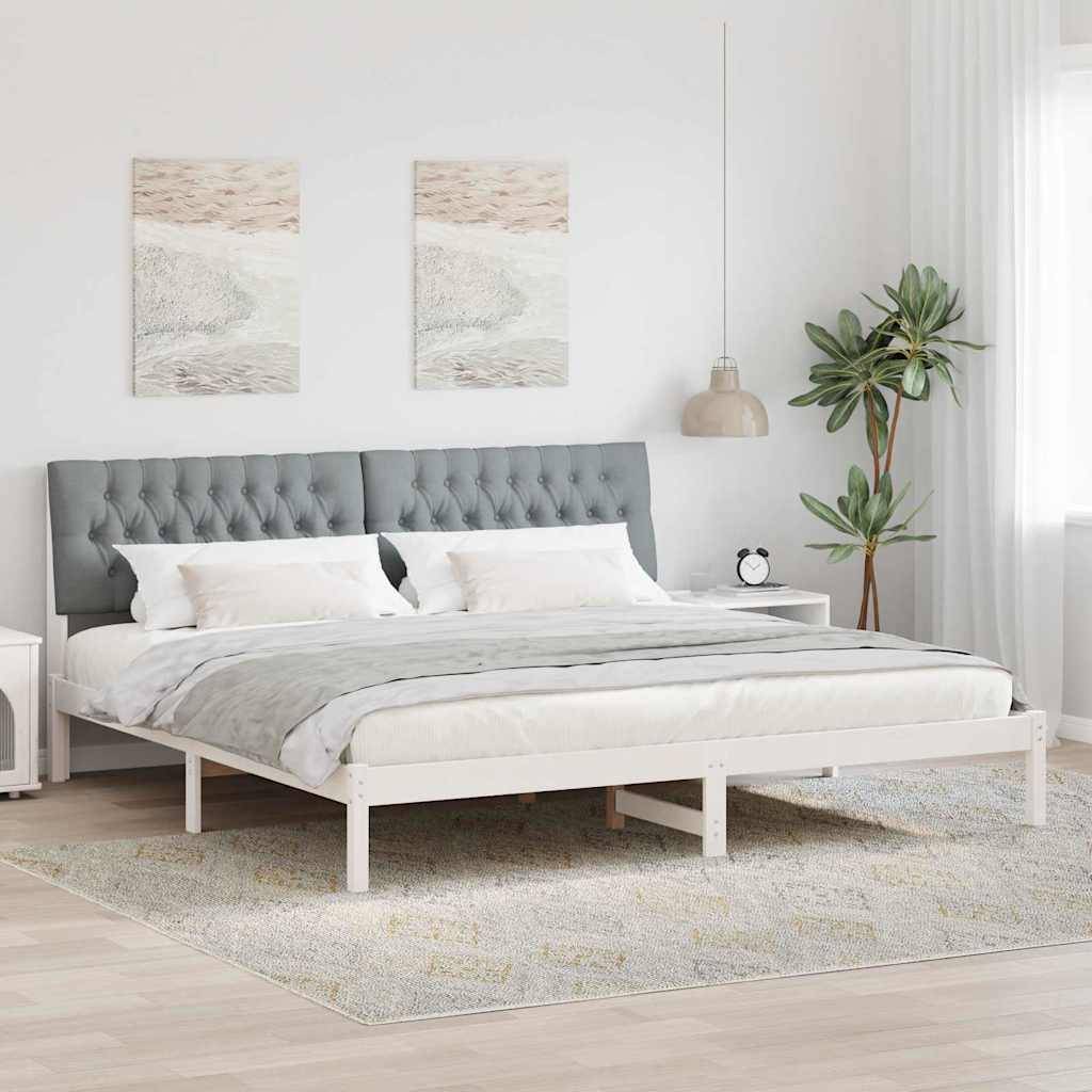 Ein modernes Schlafzimmer mit einem weißen Bett mit grauer und weißer Bettwäsche auf einem grauen Teppich. Zwei Gemälde hängen über dem gepolsterten Kopfteil.