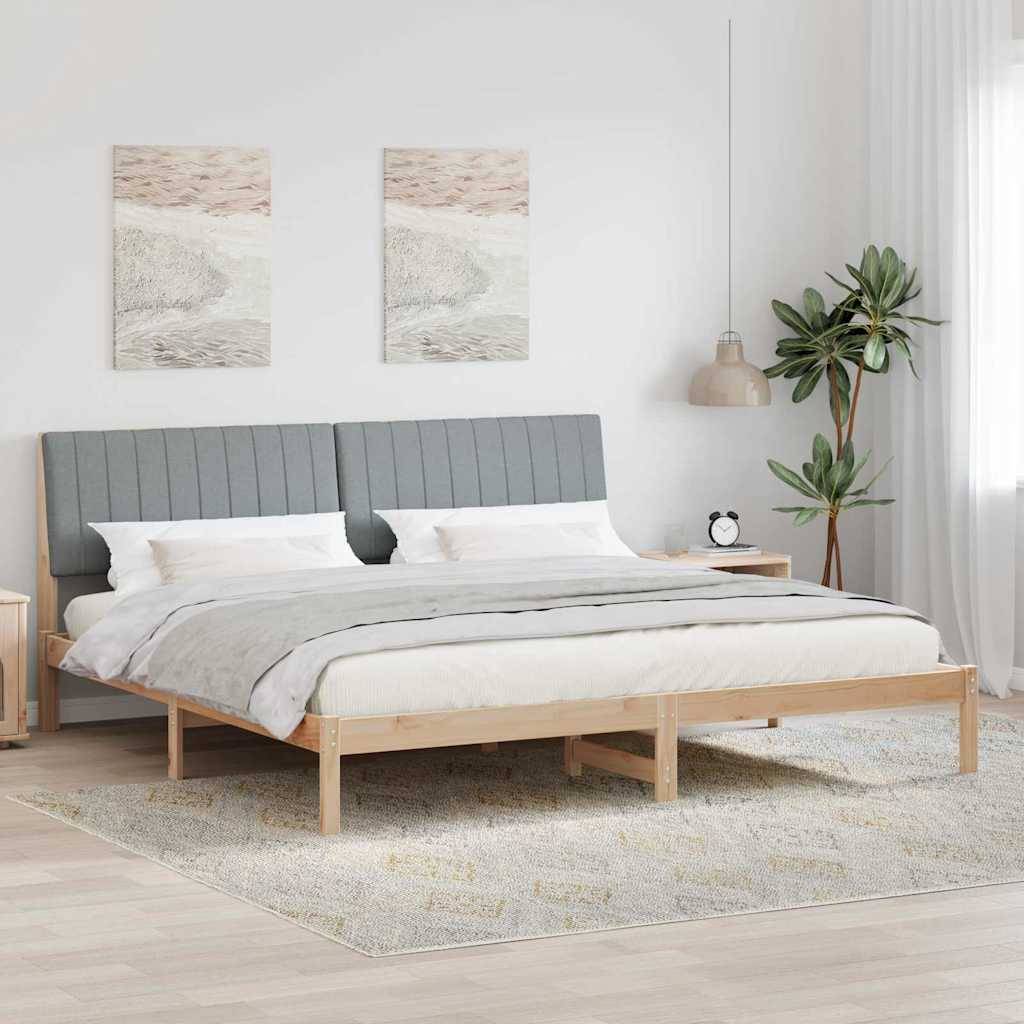 Modernes Schlafzimmer mit hellem Holzbett, grauem gepolstertem Kopfteil, weißer Bettwäsche, zwei abstrakten Wanddrucken, Pendelleuchte, Pflanze und Teppich.