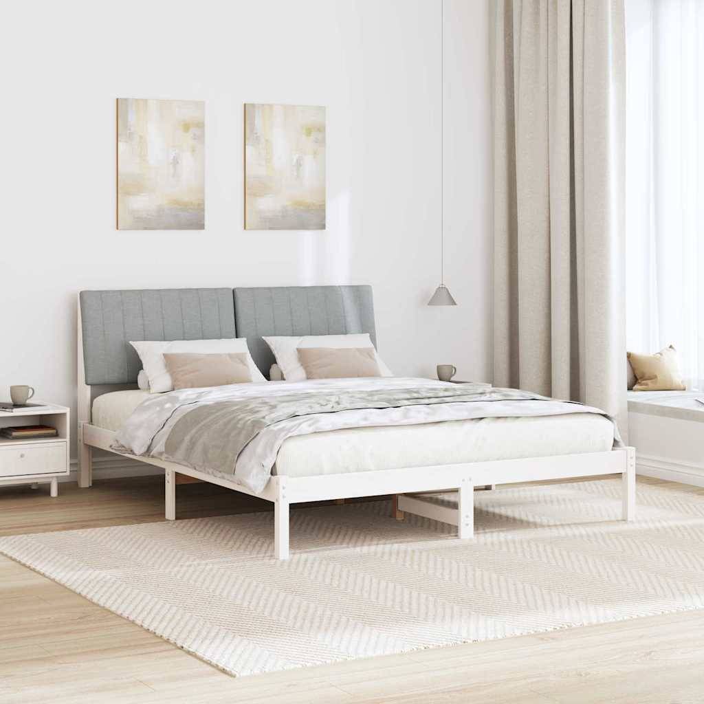 Ein modernes, lichtdurchflutetes Schlafzimmer mit einem grau gepolsterten Bett, neutraler Bettwäsche, zwei abstrakten Gemälden an der Wand und einem großen Fenster.