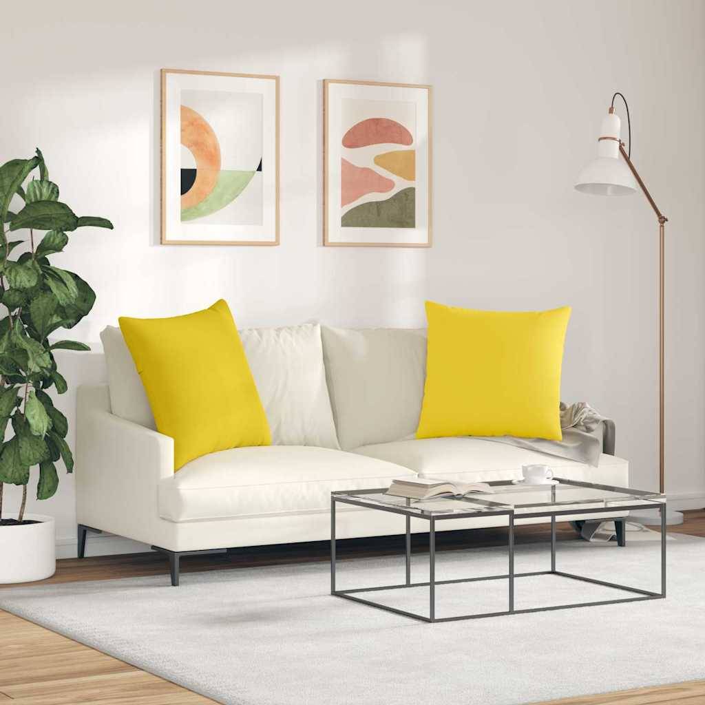 Ein modernes Wohnzimmer mit einem weißen Sofa und gelben Kissen, abstrakter Wandkunst, einer Stehlampe und einer kleinen Pflanze neben einem Couchtisch.