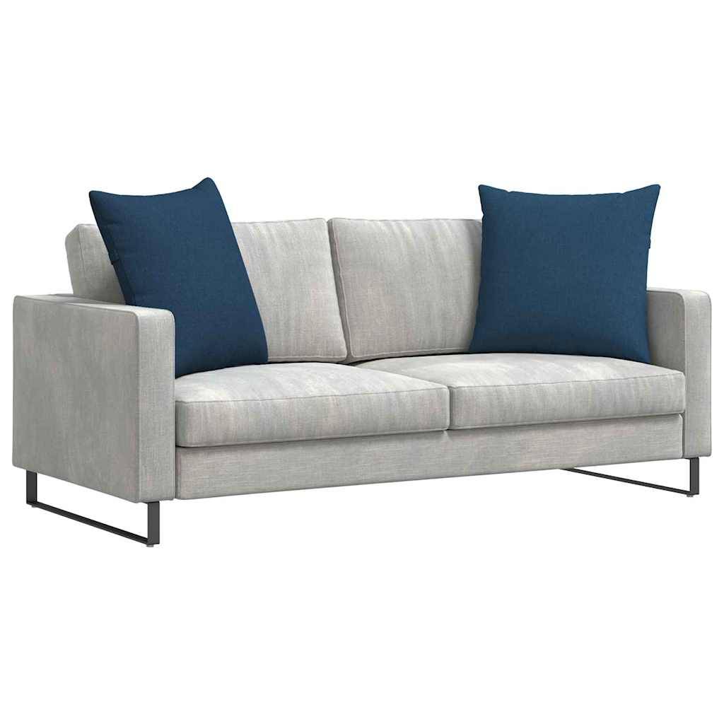 Ein modernes graues Sofa mit schlanken Metallbeinen, das zwei große blaue Kissen für zusätzlichen Komfort und Stil bietet.