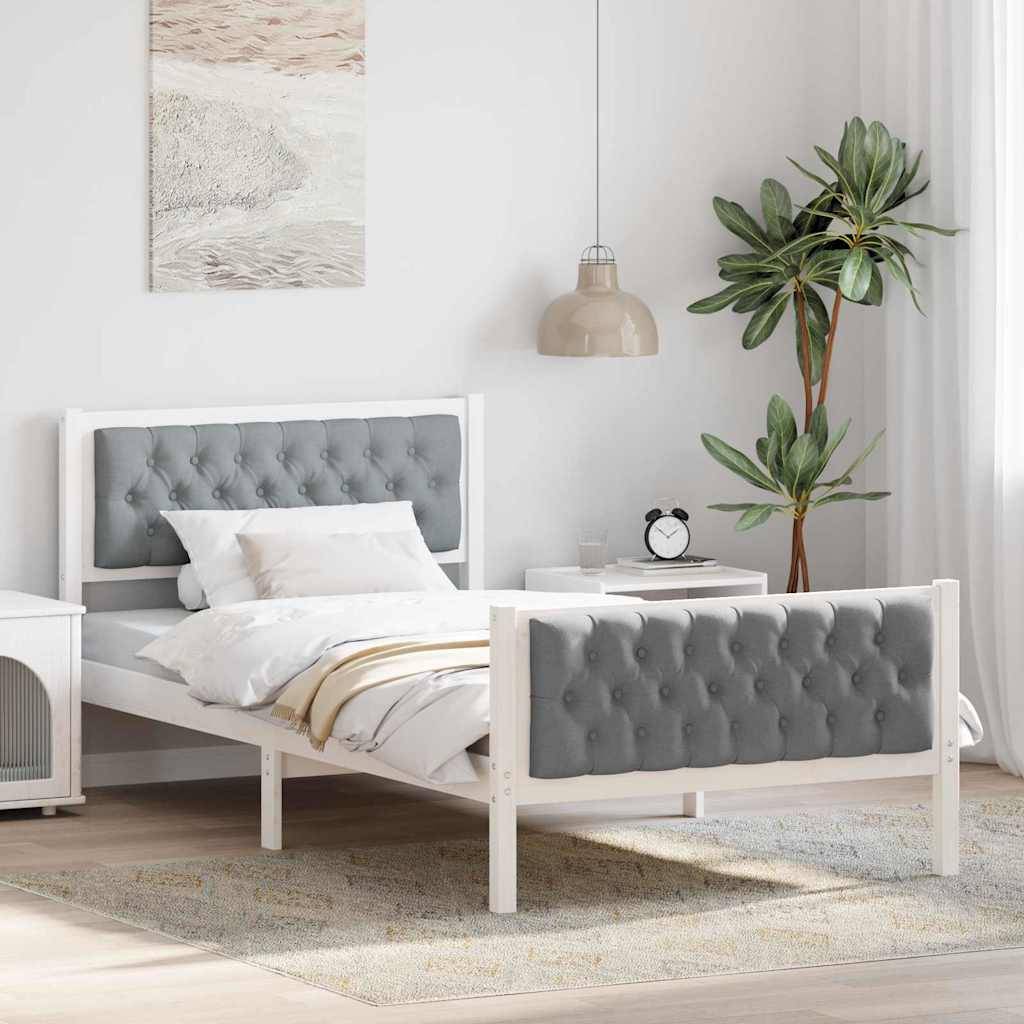 Ein modernes Schlafzimmer mit einem weißen Bett mit grauem gestepptem Kopf- und Fußteil, einem kleinen Nachttisch, einer Topfpflanze und einer hängenden Lampe.
