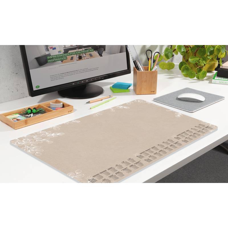 Ein aufgeräumter Büroschreibtisch mit einem Computer, auf dem ein Geschäftsdokument geöffnet ist, einem Schreibutensilien-Halter, einer Pflanze und einem großen beigen Schreibtischunterlage mit einem Kalender.