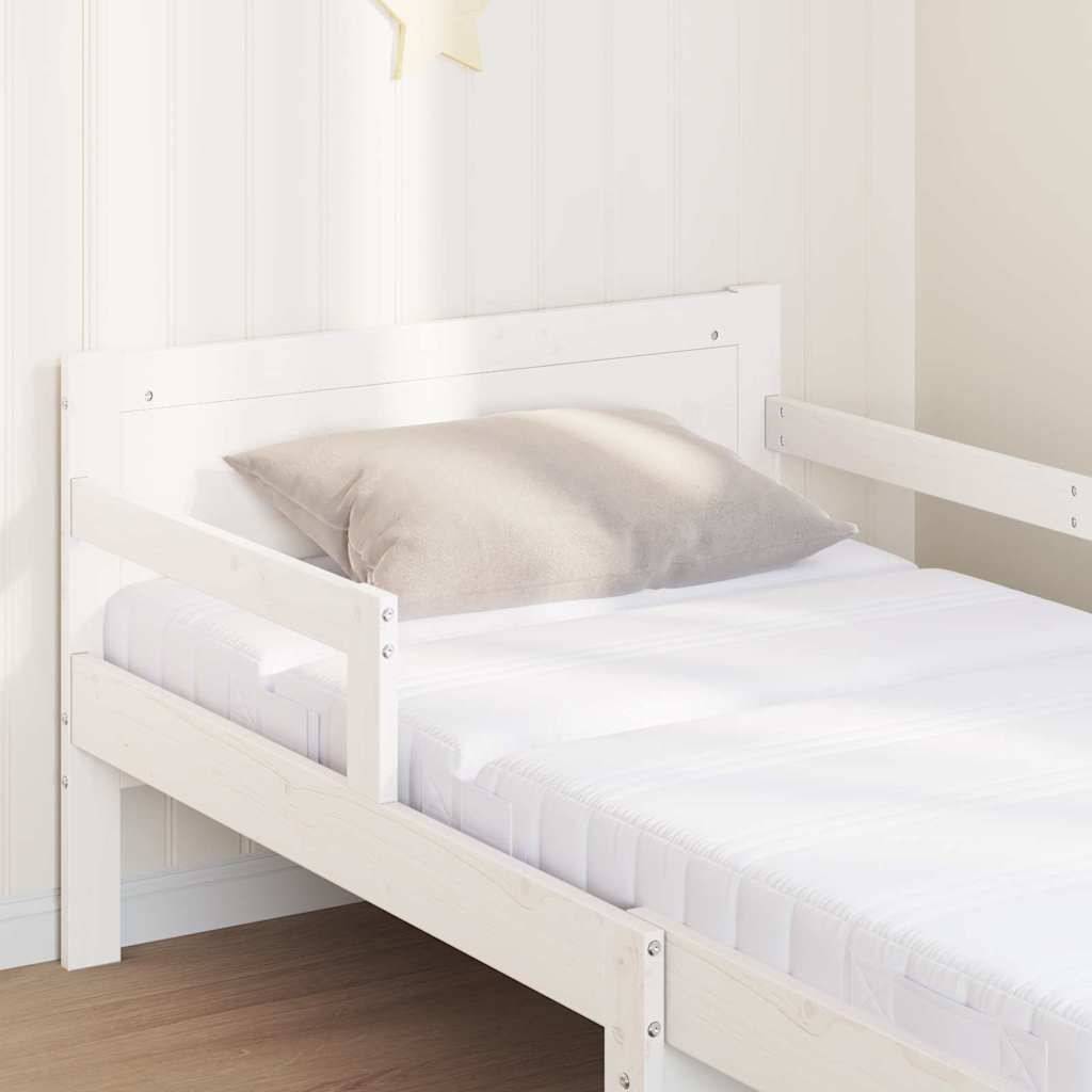 Ein weißes Holz-Kinderbett mit einem beigen Kissen steht in einem hellen Raum. Ein kleiner gelber Stern hängt an der weißen Wand über dem Bett.