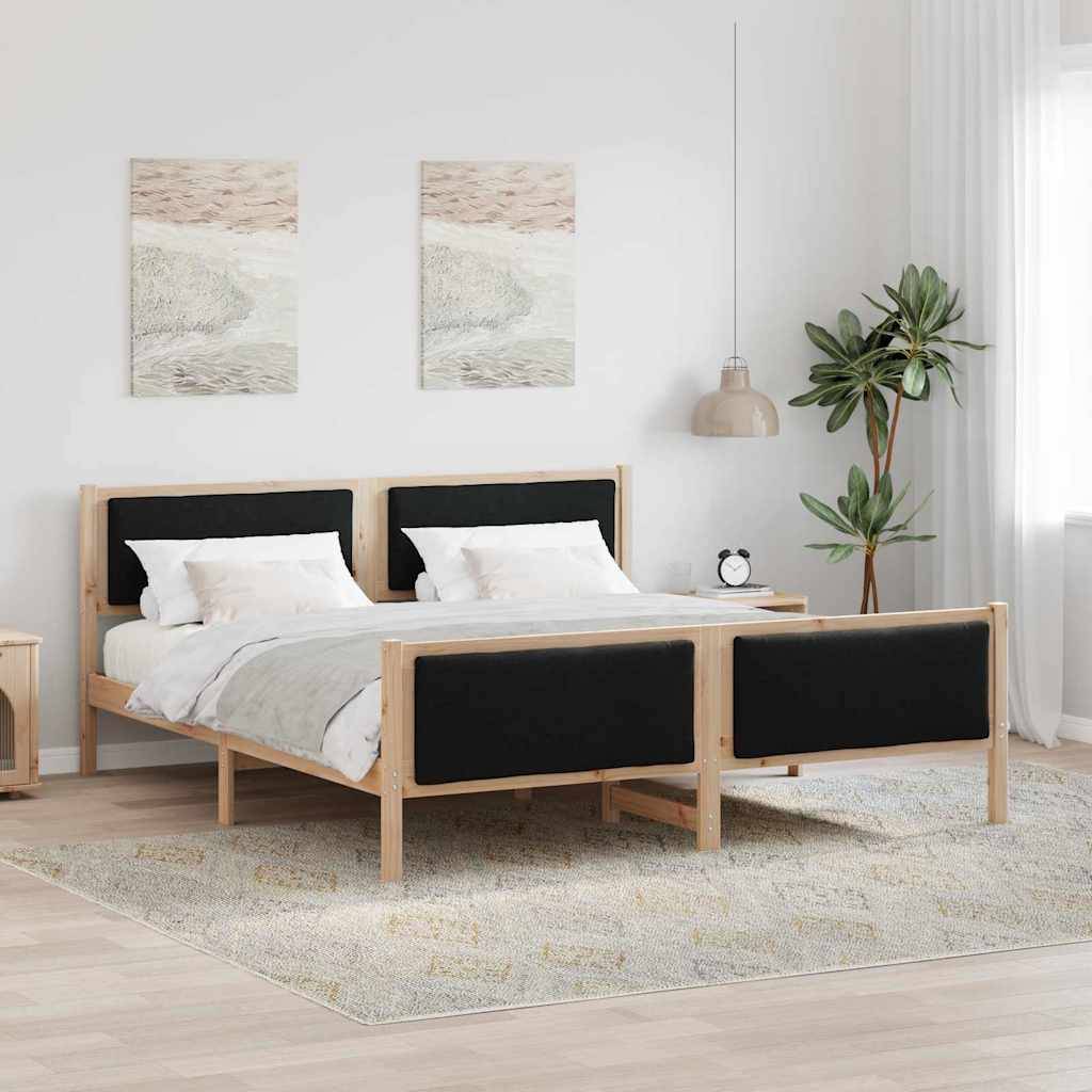 Ein modernes Schlafzimmer mit einem Holzbett, das einen schwarzen Kopf- und Fußteil hat, zwei Kunstwerke an der Wand, eine Pflanze und eine Nachttischlampe.