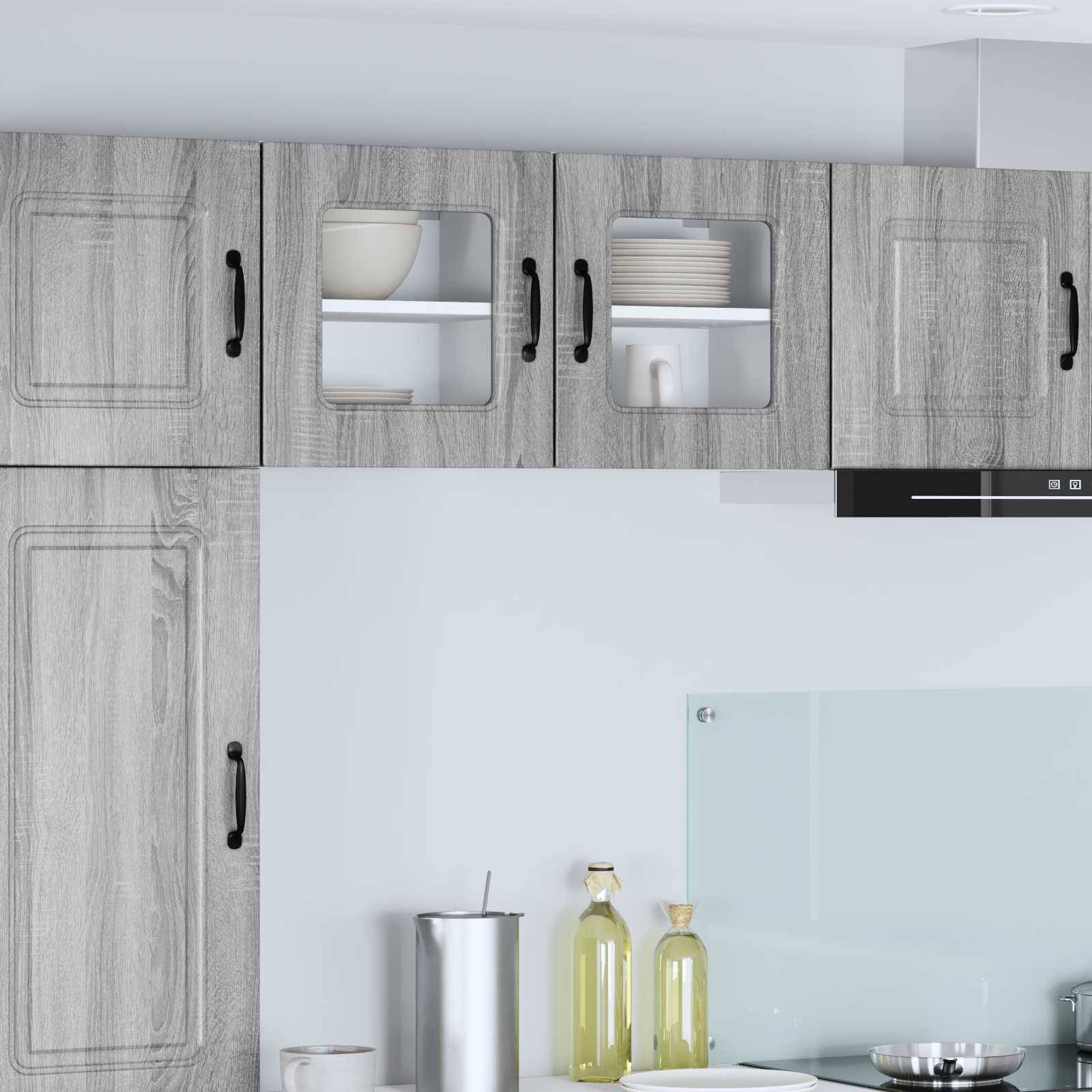 Moderne Küche mit grauen Holzschränken, Glastüren oben, die Geschirr präsentieren, und einer Arbeitsplatte mit einer Flasche und Schalen.