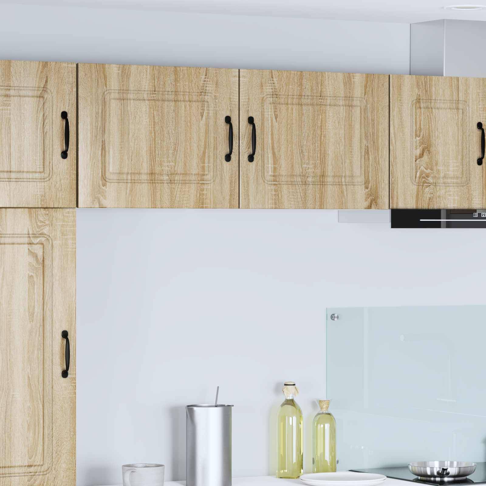 Eine moderne Küche mit Holzschränken, einer Metallwasserflasche und Olivenölflaschen auf der Arbeitsplatte unter einem hellgrauen Fliesenspiegel.