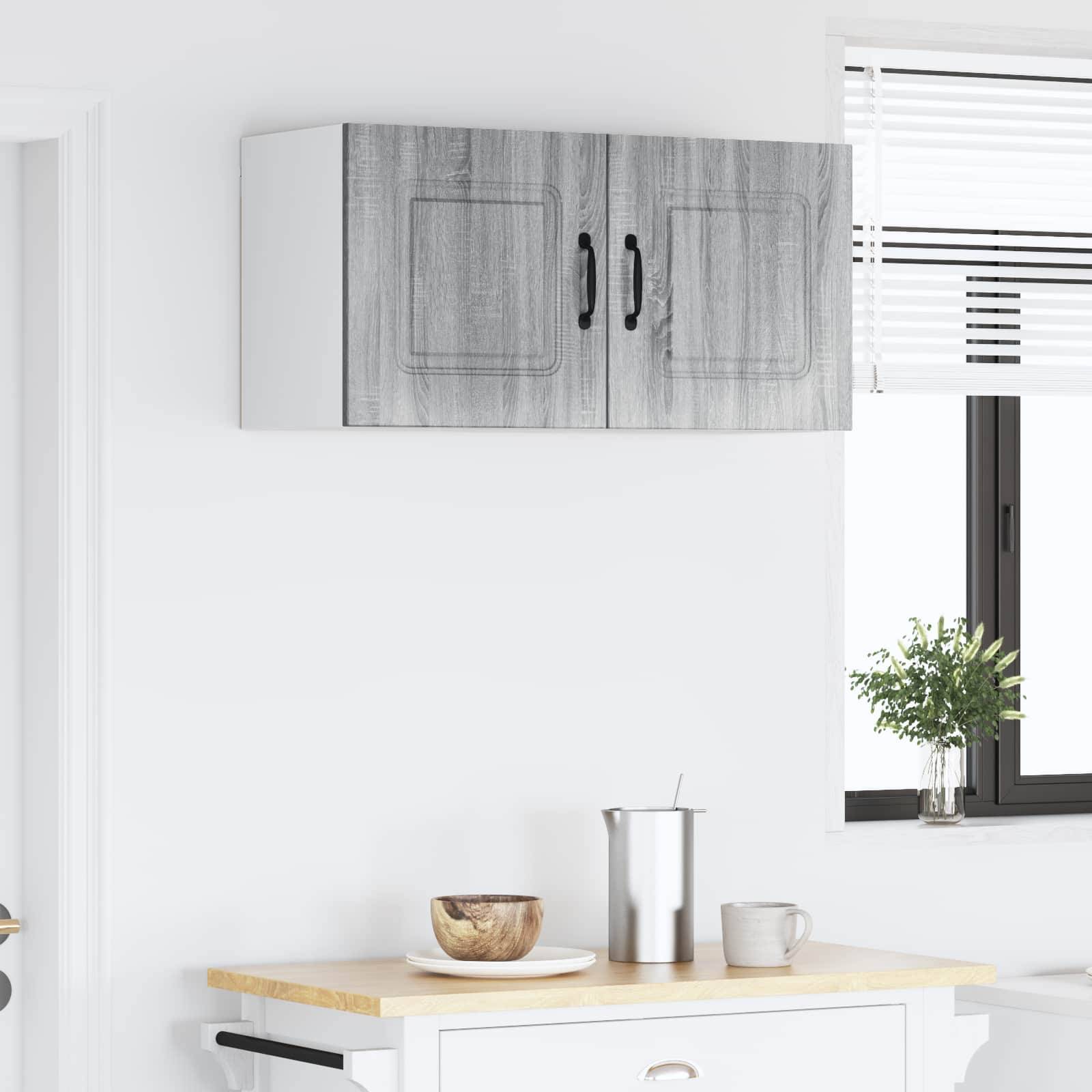 Eine minimalistische Küche zeigt eine helle Holzarbeitsplatte mit einer kleinen Schüssel, einem Metalltopf und einer Tasse. Ein Fenster lässt natürliches Licht herein.