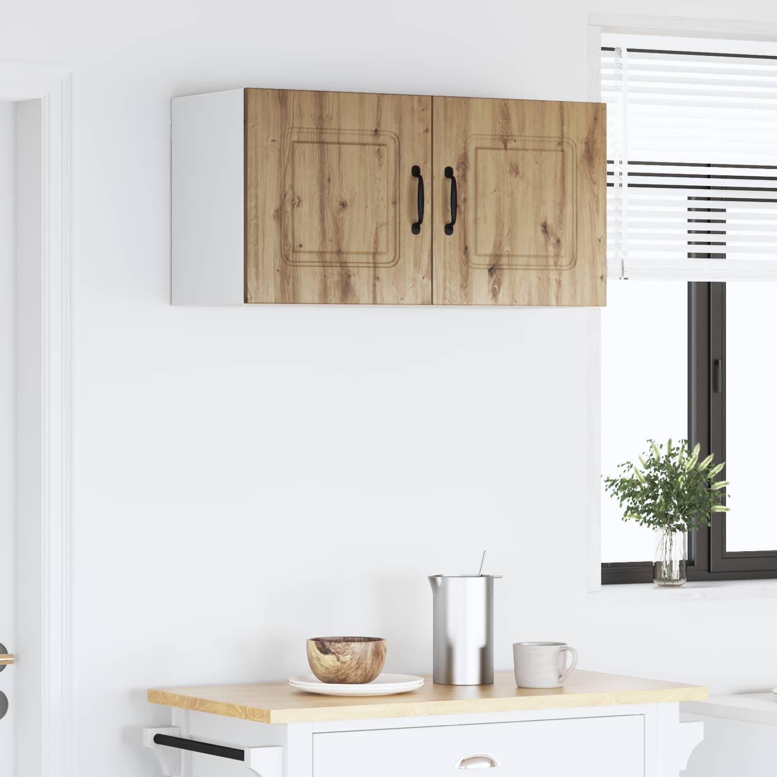 Eine weiße Küche mit Holzschränken, eine Arbeitsplatte mit einer kleinen Schüssel, einer Edelstahlflasche und einer Tasse, und ein Fenster mit Jalousien.
