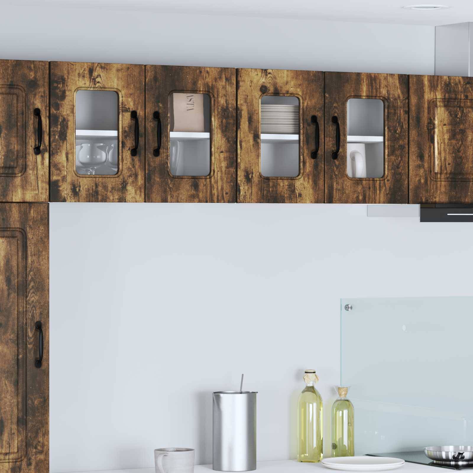 Eine Küchenszene mit Holzschränken und Glastüren, die Geschirr sichtbar machen, sowie einer Arbeitsplatte mit einem Metallbehälter, einem Glas und Olivenölflaschen.