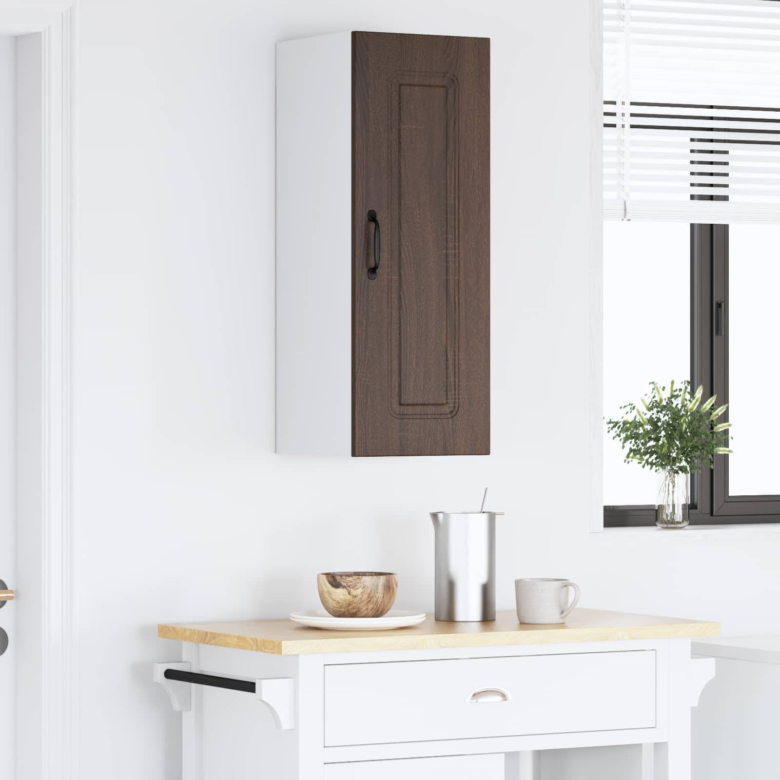Eine kleine Küchenarbeitsplatte mit einem weißen Schrank und einer Holztür darüber, eine Schüssel und einen Metallbecher. Licht von einem Fenster beleuchtet die Szene.
