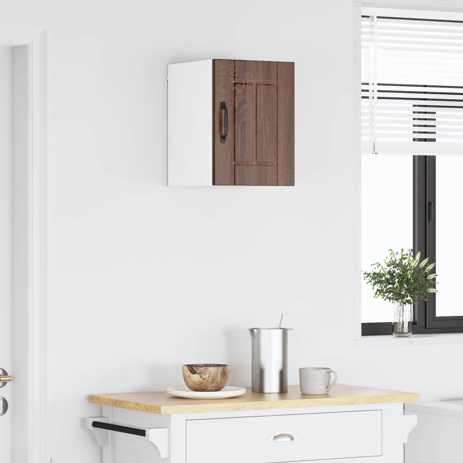 Eine moderne Küchenarbeitsplatte mit einem kleinen weißen Schrank, einer Holzschale, einem Edelstahl-Krug und einer Tasse, neben einem Fenster mit Jalousien.