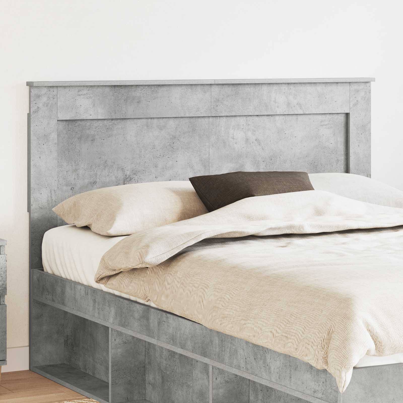 Ein modernes Bett mit hellgrauem Kopfteil und Ablagefächern darunter, bezogen mit neutraler beigefarbener Bettwäsche und einem einzelnen dunklen Kissen.